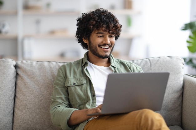 Cara de pele escura relaxada usando notebook em casa