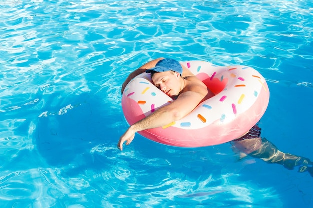 Cara descansando bêbado no círculo inflável na piscina do hotel