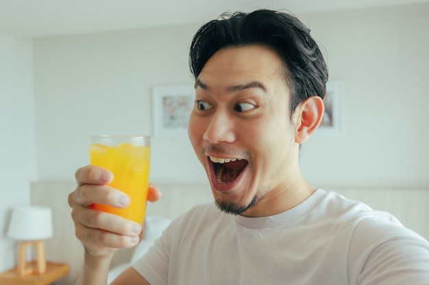 Cara divertida del hombre beber jugo de naranja fresco en el hotel para las vacaciones de verano