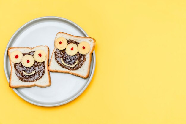 Cara divertida de monstruo en pan tostado de sándwich de halloween con queso de mantequilla de maní en el espacio de copia de fondo amarillo de la placa Niños niño dulce postre desayuno almuerzo comida