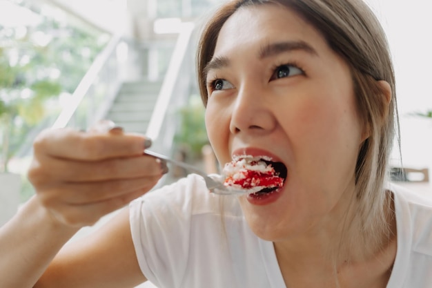 Cara divertida de una mujer feliz comiendo pastel descuidadamente en el café