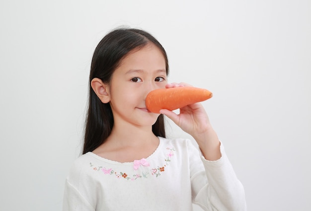 Cara divertida niña asiática haciendo nariz larga con zanahoria