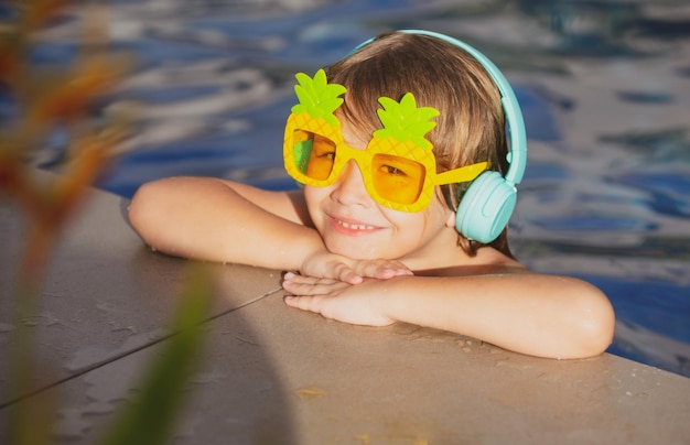 Cara divertida de niño pequeño con gafas de sol divertidas en la piscina en un día soleado vacaciones de verano para niños