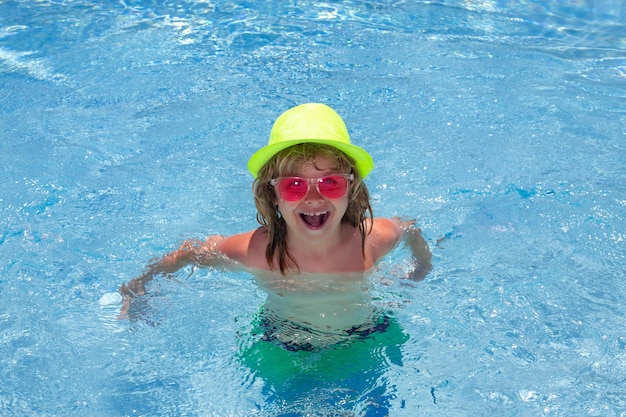 Cara divertida de los niños Niño chapoteando en la piscina Actividad de deportes acuáticos de natación en vacaciones de verano con niños