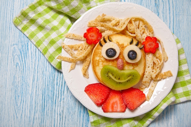 Foto cara divertida de panqueques con frutas y bayas