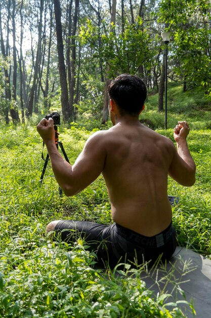 Cara do milênio meditando com treinador on-line via conexão tablet ipad na floresta transmitindo on-line sua aula e instruções méxico