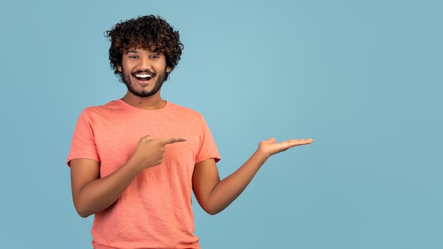 Cara do Oriente Médio sorridente apontando para algo na palma da mão