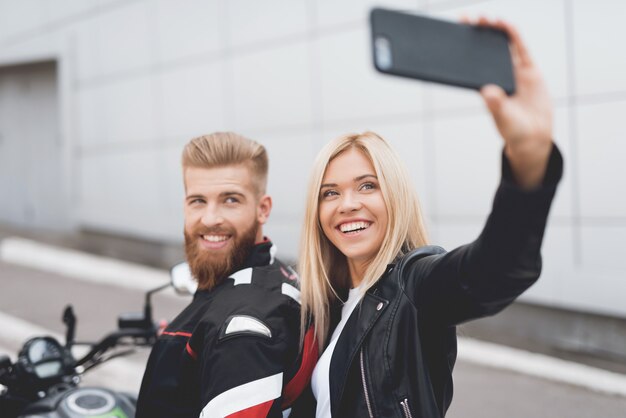 Cara e garota fazendo selfie, sentado em uma motocicleta elétrica.