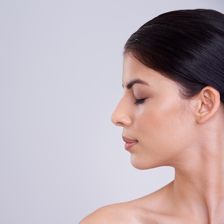 Foto cara e perfil de mulher calma com cosméticos tratamento facial ou cuidados com a pele em um fundo cinza de estúdio pessoa bruneta ou modelo jovem com sorriso em satisfação com a beleza ou maquiagem em maquete