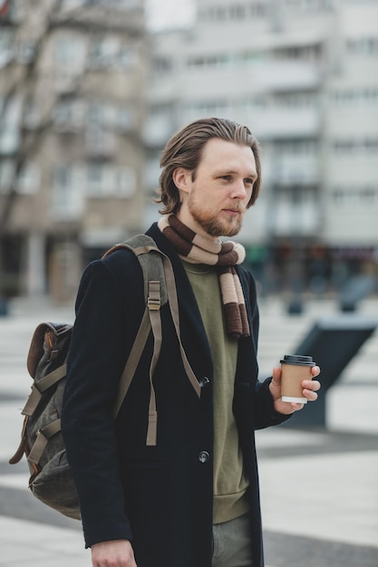 Cara elegante de cachecol e casaco com uma xícara de café para viagem na rua de Wroclaw Polônia