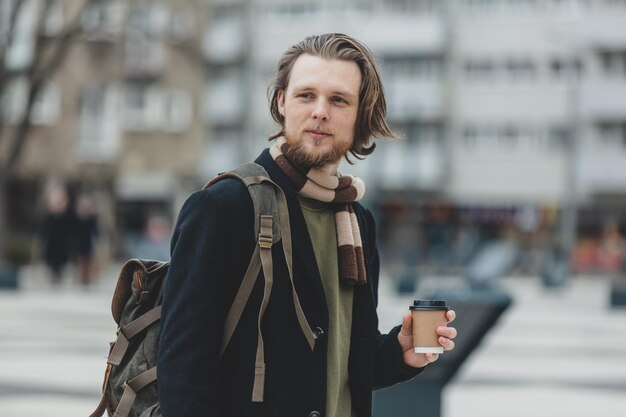 Cara elegante de cachecol e casaco com uma xícara de café para viagem na rua de wroclaw polônia