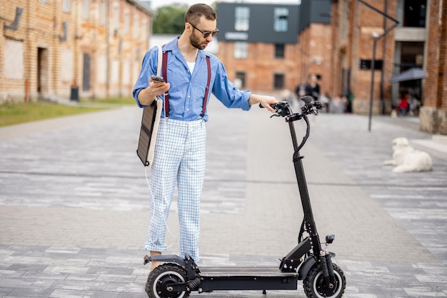 Cara elegante fica com scooter elétrico ao ar livre