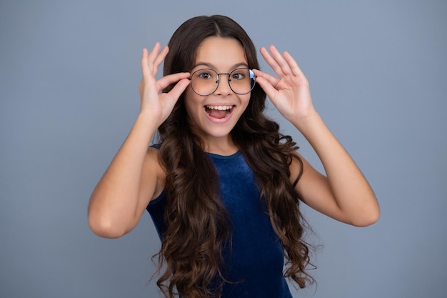 Cara emocionada emociones alegres de niña adolescente Niño adolescente con gafas sobre fondo gris de estudio Linda chica en anteojos