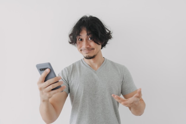 Cara engraçada e feliz do homem olha para o seu smartphone em fundo branco