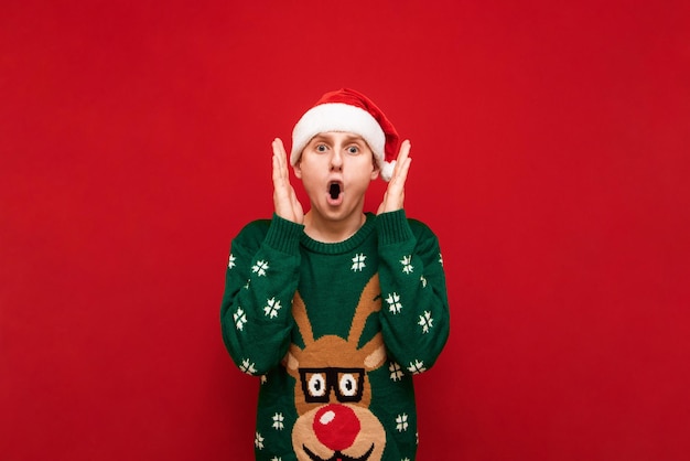 Foto cara espantado com chapéu de papai noel isolado em fundo vermelho