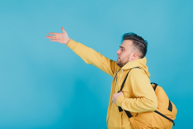 cara esportivo em um suéter amarelo com uma mochila amarela em um fundo azul