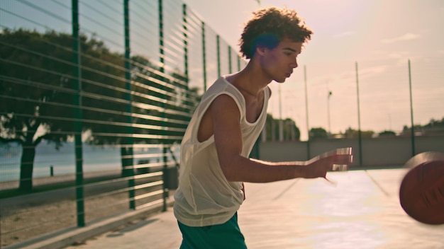 Cara esportivo jogando basquete na luz solar closeup adolescente pulando treinamento