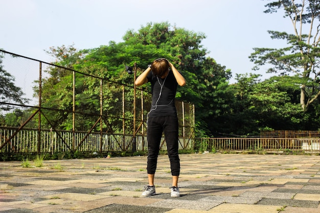 Cara esportivo usando fones de ouvido aquecendo antes de correr treino de corrida