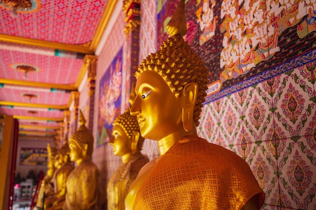 La cara de la estatua dorada de Buda está aislada en una pared.