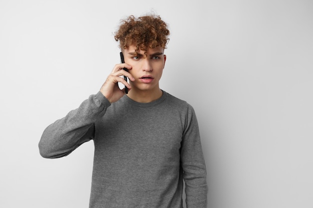 Cara excêntrico falando ao telefone posando fundo isolado de emoções