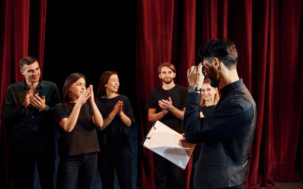 Foto cara expressivo praticando seu papel grupo de atores em roupas de cor escura no ensaio no teatro