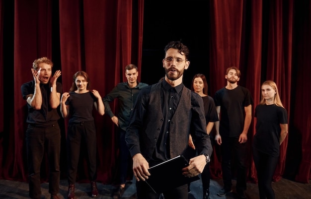 Cara expressivo praticando seu papel Grupo de atores em roupas de cor escura no ensaio no teatro