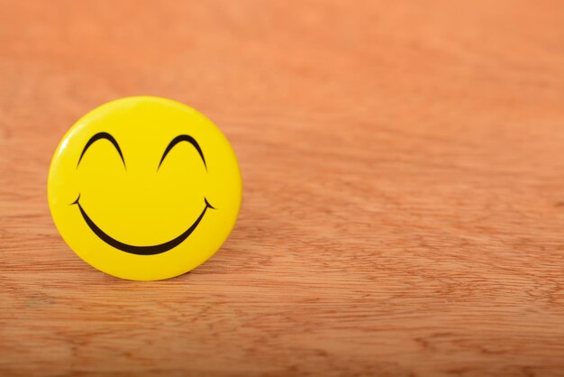 Cara feliz amarilla con sonrisa aislada en un fondo de madera