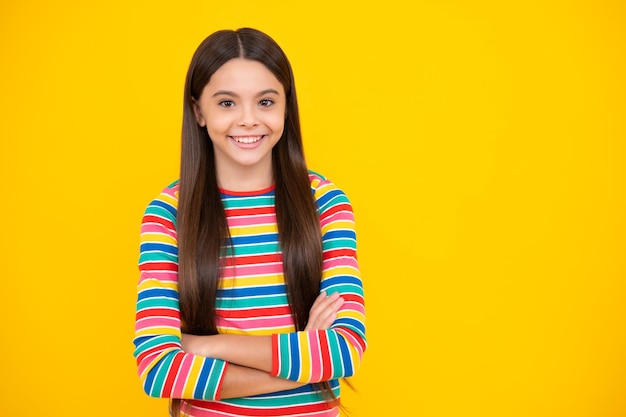 Foto cara feliz emociones positivas y sonrientes de niña adolescente copiar espacio linda niña adolescente cruzando los brazos sobre fondo amarillo