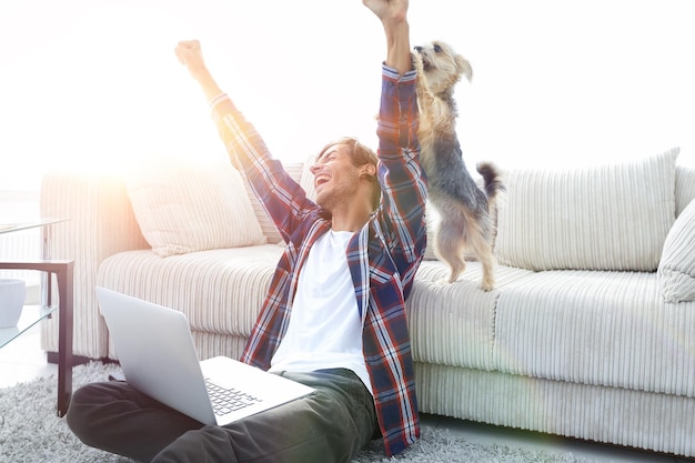 Cara feliz exulta com seu cachorro sentado perto do sofá na sala de estar