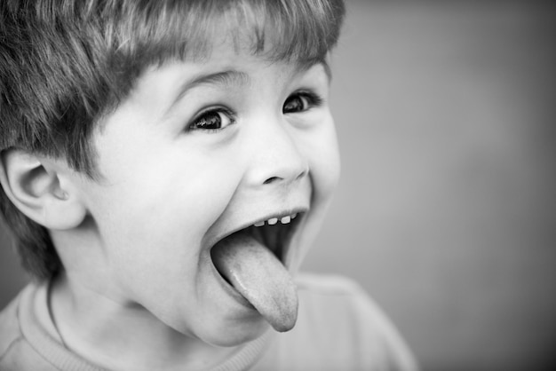 Cara graciosa de los niños Primer plano retrato de un niño pequeño y lindo mostrar lengua Concepto de infancia Lengua fuera