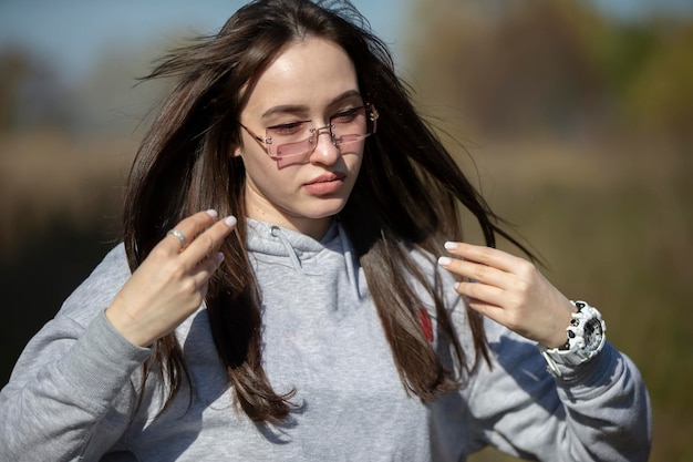 La cara de una hermosa joven que se alisa el pelo y no mira a la cámara.