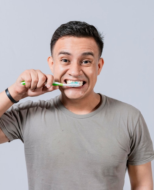 Cara de hombre guapo cepillándose los dientes Concepto de cuidado y cepillado de dientes Cara de chico cepillando dientes aislado Concepto de sonrisa oral y dental Hombre sonriente cepillándose los dientes aislado