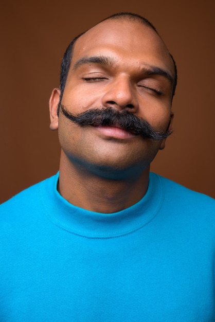 Cara de hombre indio con bigote vistiendo suéter azul