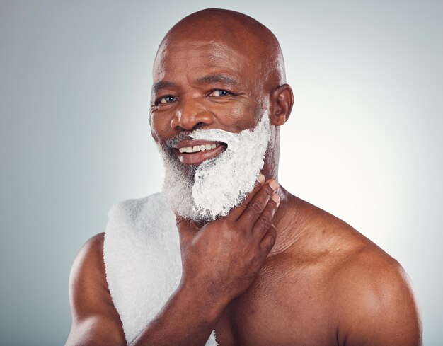 Cara de hombre negro y sonrisa de crema de afeitar en retrato de belleza y aseo aislado en el fondo del estudio Eliminación de vello facial persona mayor feliz e higiene con brillo y bienestar para el cuidado de la piel