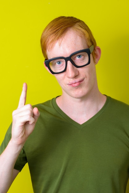 Cara de hombre nerd con pelo rojo con anteojos y apuntando hacia arriba