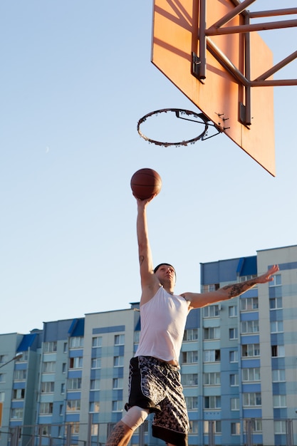 cara jogando basquete no campo de esportes.