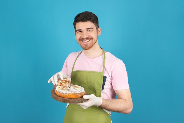 Foto cara jovem bonito sorridente segurando bolo caseiro fresco.