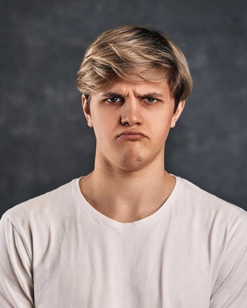 Cara jovem chateado em camiseta em fundo cinza