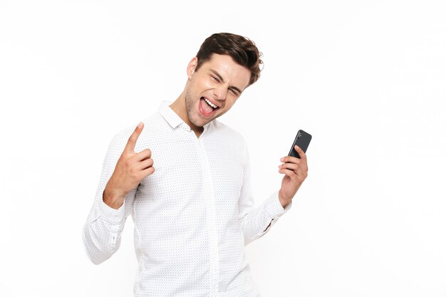 Cara jovem, com cabelo escuro curto, gritando enquanto segura o smartphone