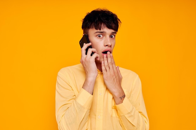 Cara jovem de camisa amarela falando ao telefone fundo isolado