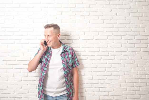 cara jovem falando ao telefone em um fundo de parede branca