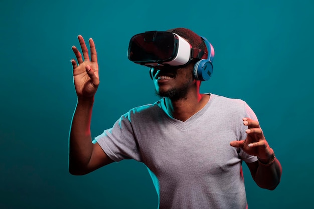 Cara jovem, levantando as mãos para jogar um jogo futurista com óculos vr, anunciando simulação 3d interativa na tecnologia de óculos. Pessoa milenar desfrutando da experiência de fone de ouvido de realidade virtual.