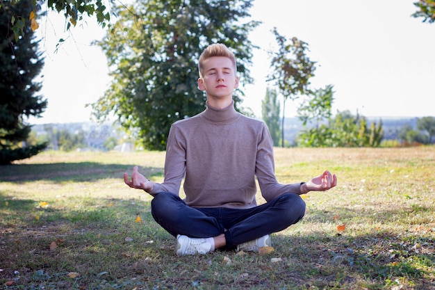 Cara jovem, meditando no parque. Coloque sob a inscrição.