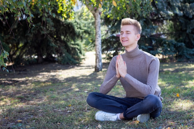 Cara jovem, meditando no parque. coloque sob a inscrição.