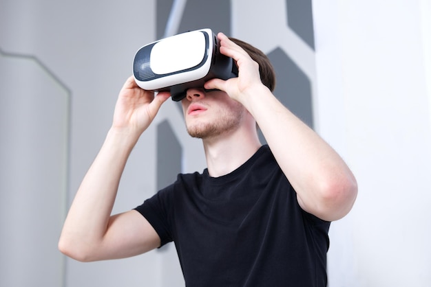 Cara jovem usando dispositivo moderno fone de ouvido de máscara de realidade virtual VR ou óculos 3D AR metaverse