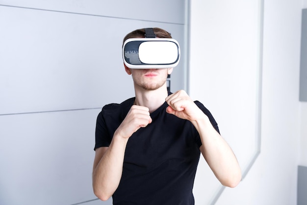 Cara jovem usando dispositivo moderno fone de ouvido de máscara de realidade virtual VR ou óculos 3D AR metaverse