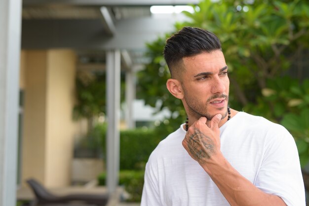 Cara de joven guapo persa barbudo pensando con la naturaleza al aire libre