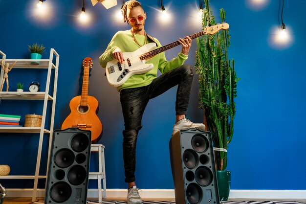 Cara legal com dreads praticando tocando guitarra em casa