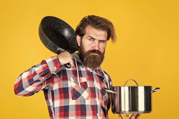 Cara maduro na camisa quadriculada com pan homem elegante vai cozinhar comida homem barbudo com bigode usar utensílios de cozinha comendo chef de superfície antiaderente saudável cozinhando o jantar Catering by design