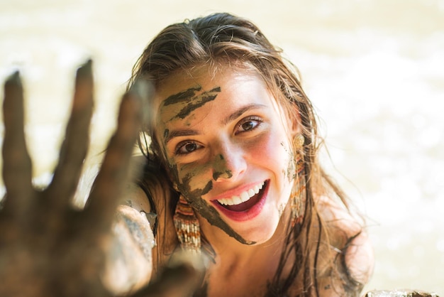 Cara y manos de mujer cubiertas de barro. Exfoliante de barro saludable.